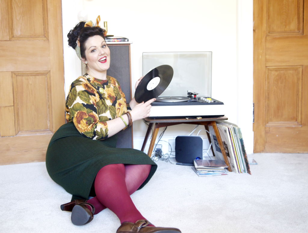 Hayley Angell founder of Love is in the Detail wears outfit from Vintage Style Challenge while playing a record.